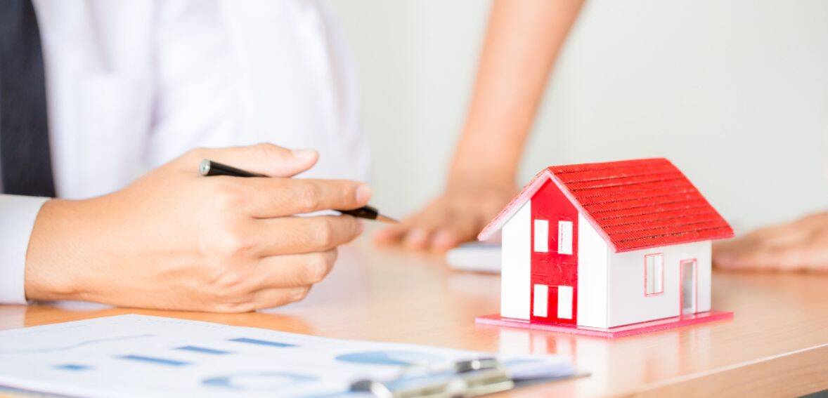 a person holding a pen and a small model house
